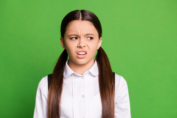 可爱的小女士在黑板前的照片看空的空间鬼脸傲慢的一个学生无聊的作文课愚蠢的问题穿制服白色衬衫孤立的绿色背景图片下载