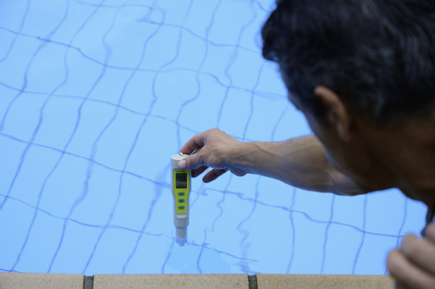 男子手持电子仪器检查池水的pH值及消毒情况图片下载