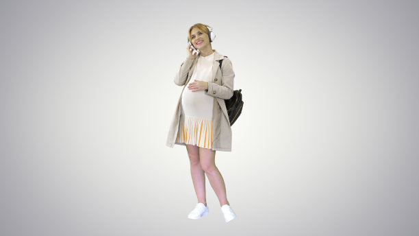 孕妇站在草地上戴着耳机听音乐图片下载