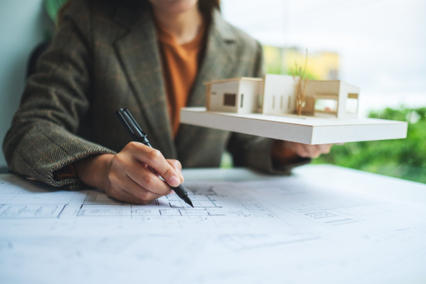 一名女建筑师拿着设计图纸在建筑房子模型上工作图片下载
