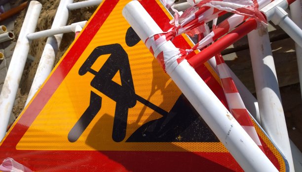 指示建筑工程的道路工程标志及地面上的金属栅栏。关闭了。红色和黄色сolour。恢复和重建的概念。交通障碍。提供安全控制。图片下载