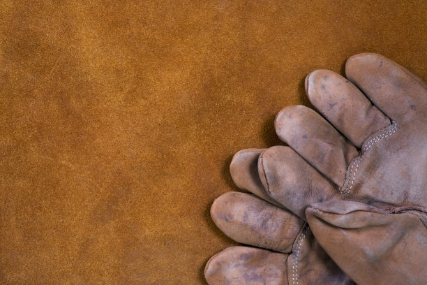 我们的工作手套在绒面革工作围裙作为背景。图片下载