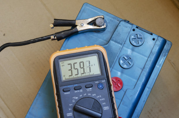 万用表放在汽车电池上。图片下载