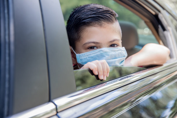 小学生戴着防护面罩，从车窗往外看图片下载