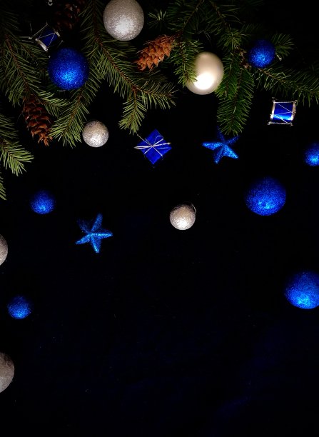 带有锥形的冷杉树枝和黑色背景上的蓝色圣诞装饰品图片下载