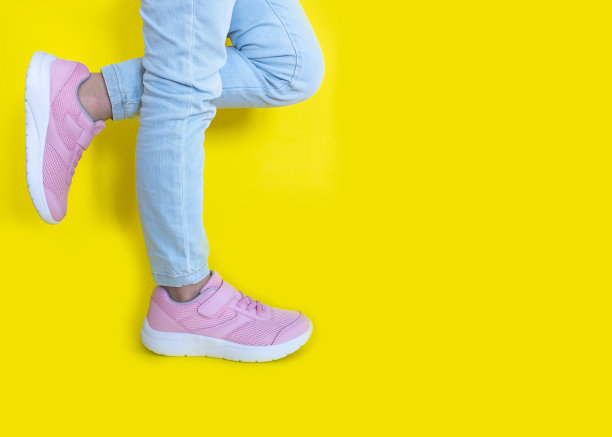 黄色背景的粉色运动鞋和蓝色牛仔裤。模型。本空间图片下载
