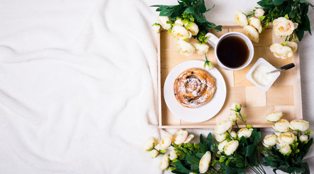 俯视图的早餐，面包，茶和酸奶在木托盘和鲜花图片下载