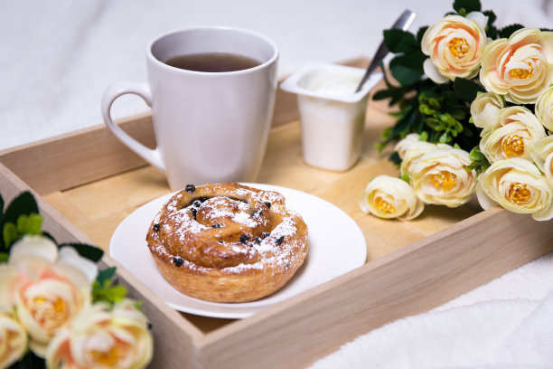 木盘上放着面包、茶、酸奶和鲜花图片下载