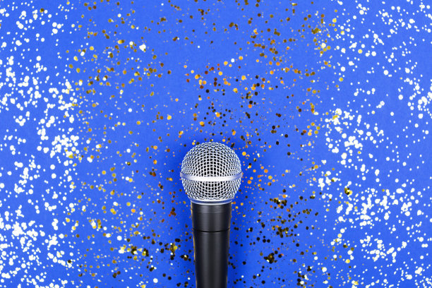 蓝色背景上装饰着五彩纸屑的麦克风。最小的原料油。图片下载