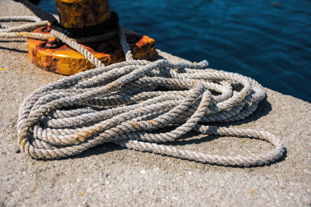 在港口生锈的系柱旁的旧卷绕绳的特写图片下载