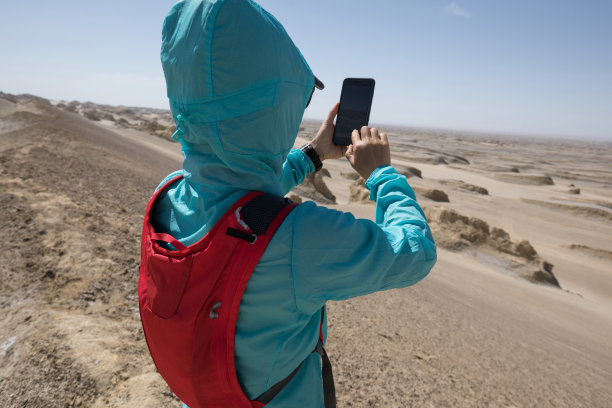 成功的女性徒步旅行者使用智能手机拍摄沙漠照片图片下载