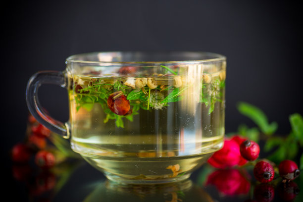 由各种草药制成的热茶，放在玻璃杯中，以黑色为背景图片下载