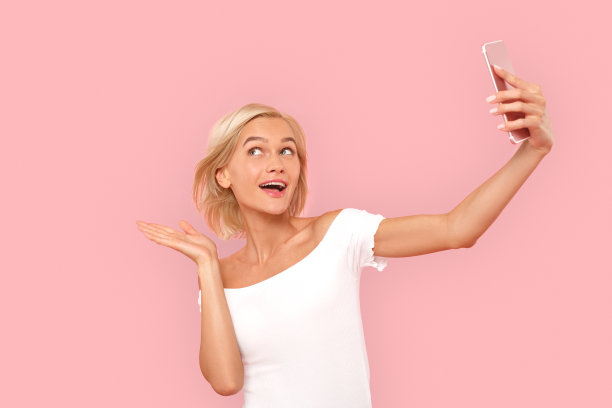 年轻的成年女子在用智能手机自拍图片下载