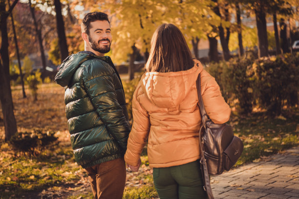 背影背影脊柱视图照片迷人的夫妇走在十月城市中心公园手牵手穿帆布背包图片下载