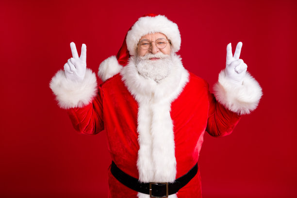 圣诞老人的照片，圣诞新年派对，做v符号，穿红色的服装，白色的手套，黑色的皮带隔离在明亮的照耀颜色的背景图片下载