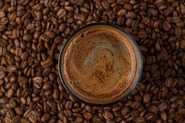 顶视图的热咖啡杯和模糊的咖啡豆。图片下载