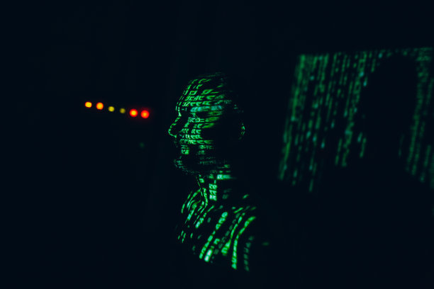 在黑暗中脸上有绿色抽象字母的年轻人。图片下载