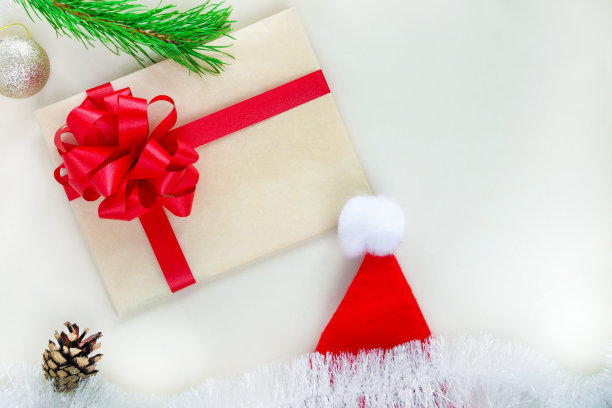 牛皮纸信封用红丝带系着，圣诞老人帽子。圣诞和新年作文。平躺图片下载