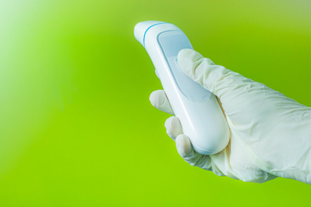 戴着手术手套的人手在绿色背景上检查体温图片下载