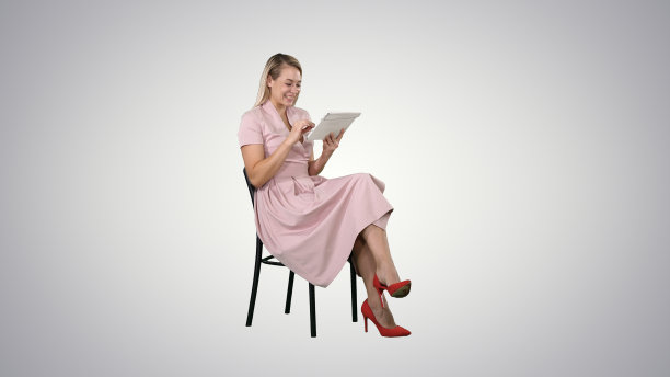 穿着粉红色裙子的有趣漂亮的年轻女人和我们一起坐在椅子上图片下载