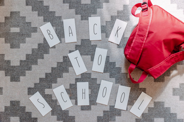 回到学校平躺在灰色的地毯上，背着红色的背包在附近。图片下载