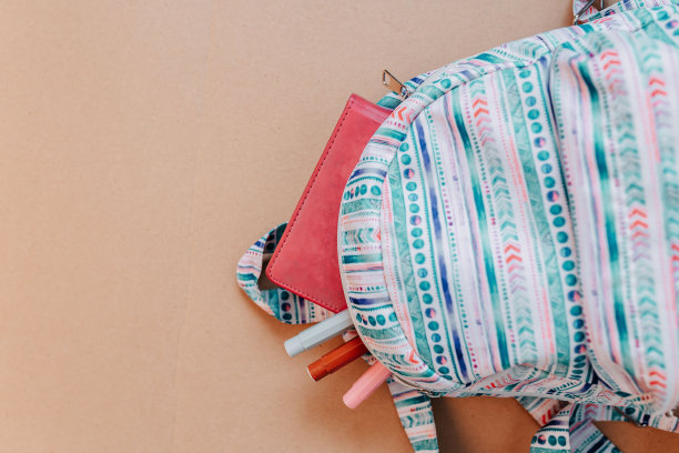 学校用品平铺在牛皮纸背景上。蓝色背包，白色耳机，笔记本和有拷贝空间的笔。图片下载