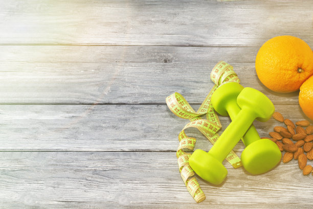 很多橘子，哑铃，卷尺在木质纹理的背景上。健身,运动营养。图片下载