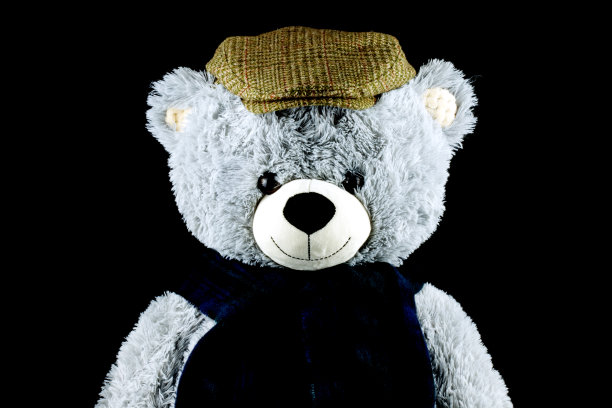 泰迪熊戴平帽和围巾在黑色的背景图片下载