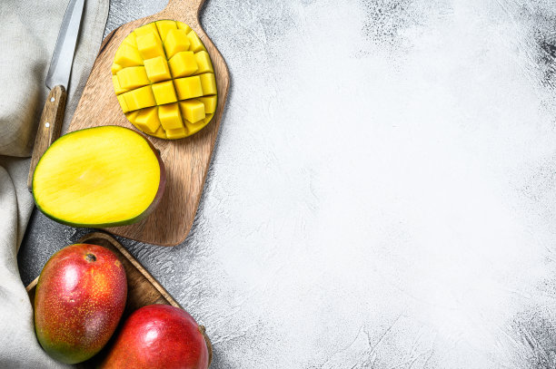芒果在切菜板上切成小方块。灰色的背景。前视图。本空间图片下载
