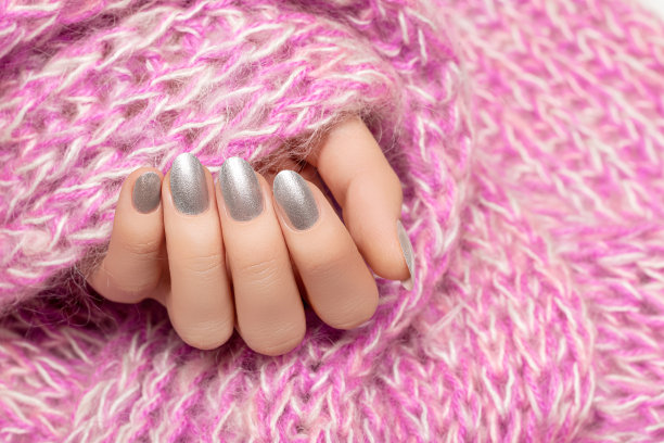 女性手与银指甲设计。银色指甲油修剪过的手。女人手里拿着粉色羊毛披肩。图片下载