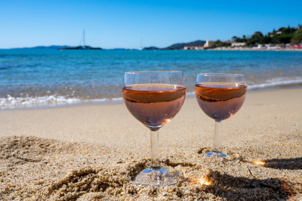 两杯当地的玫瑰葡萄酒在白色的沙滩和蓝色的地中海背景，靠近勒Lavandou，法国普罗旺斯图片下载