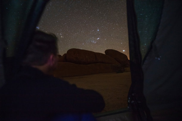 汽车和岩石。在帐篷里看星星的人。图片下载