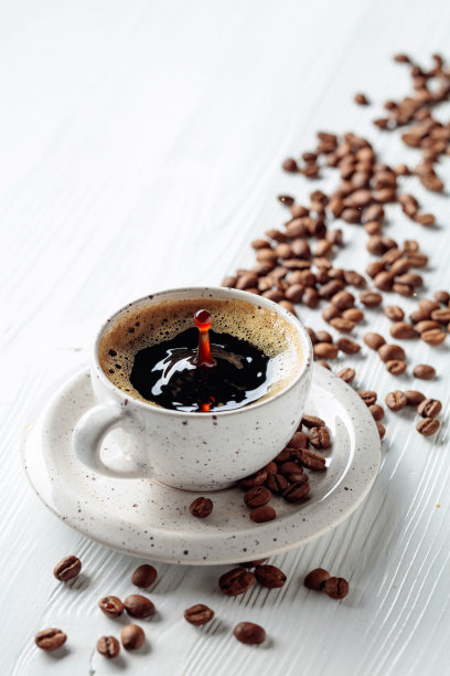 白木桌上放着黑咖啡和咖啡豆。图片下载