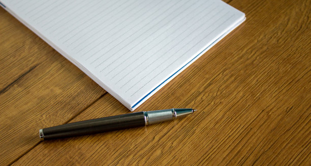笔记本和钢笔放在木桌上。商业教育理念。图片下载