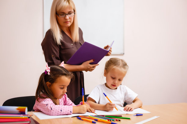 两个快乐的小女生在课堂上学习，老师解释说图片下载