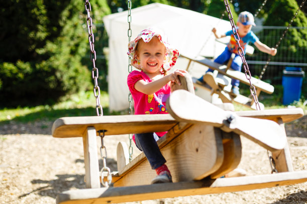 一个骑着旋转木马的可爱小女孩。女孩把她的手像飞机的翅膀。图片下载