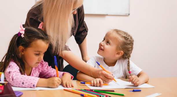 两个快乐的小女生在课堂上学习，老师解释说图片下载