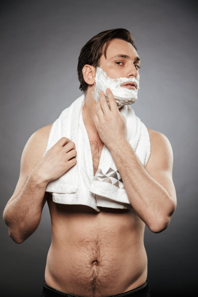 半裸成年男子把剃须泡沫与毛巾在他的脖子上的全长照片，孤立的灰色背景图片下载