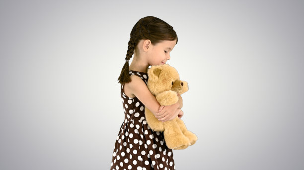 小女孩穿着圆点裙子，抱着大泰迪熊散步图片下载