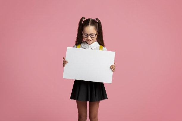 私立学校。戴眼镜和穿校服的小女孩用空的桌子图片下载