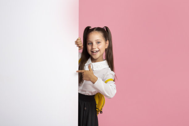 穿着校服的小女孩从空无一物的广告牌上爬出来，用手指着它图片下载