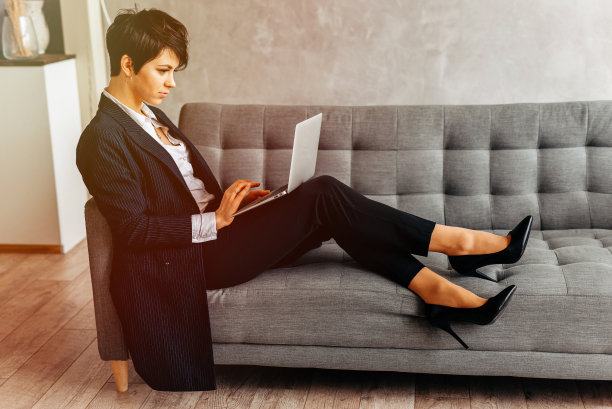 穿着戏服和高跟鞋坐在沙发上使用笔记本电脑的女人图片下载