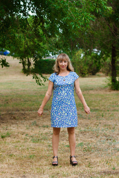 一个穿着蓝色裙子的金发女郎站在城市公园里。图片下载