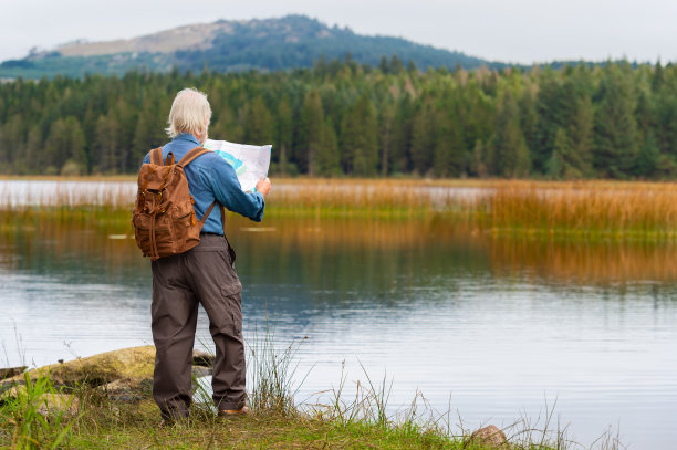 在一个阴天的夏日，一个活跃的老人站在苏格兰的一个湖边，一边看地图一边休息图片下载