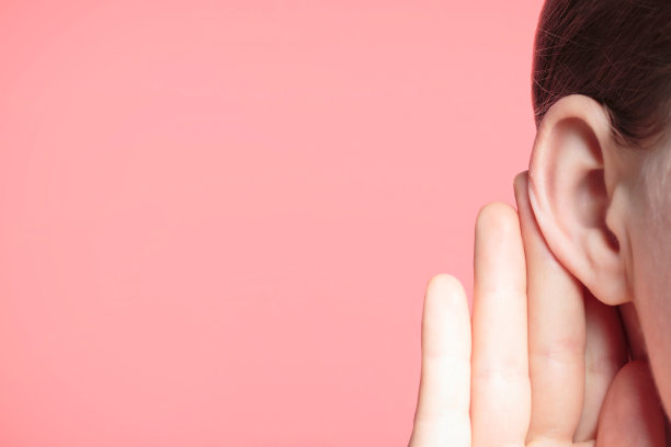 女孩在粉红色的背景下，用手掌对着耳朵专心地听着，新闻概念图片下载