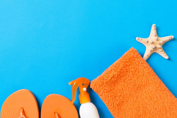俯视图海滩平铺配件。防晒霜瓶子，贝壳，海星，毛巾和人字拖彩色背景和复制空间图片下载