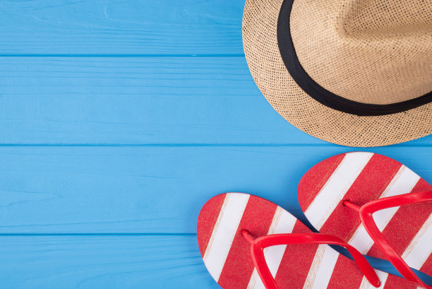 休假时间的概念。上面的头顶上的照片条纹拖鞋和帽子孤立在蓝色木制背景与copyspace图片下载