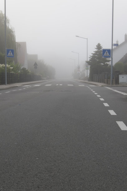 清晨的大雾弥漫在空旷的路上。斑马线几乎看不见。图片下载
