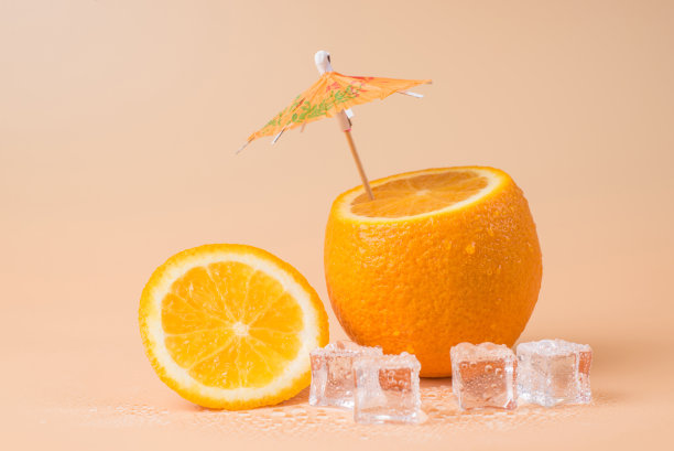 特写照片切橙与鸡尾酒伞在它和冰块孤立在沙地背景图片下载