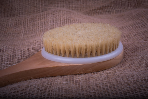用刷子在粗麻布表面擦干皮肤。改善皮肤健康的美容理念。图片下载